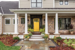 A luxury home with a bright yellow front entry door.